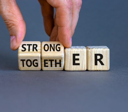 Stronger together symbol. Businessman turns cubes and changes the word together to stronger. Beautiful grey background, copy space. Business, motivational and stronger together concept.