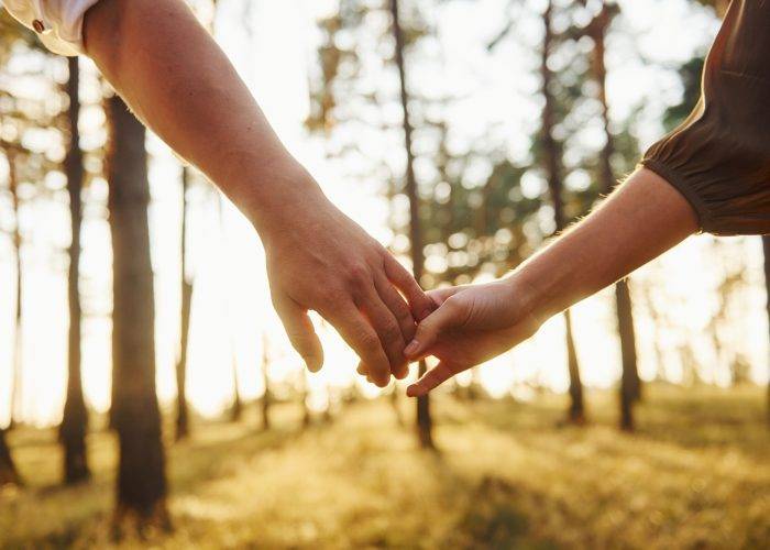 Close up view of hands. Happy couple is outdoors in the forest at daytime