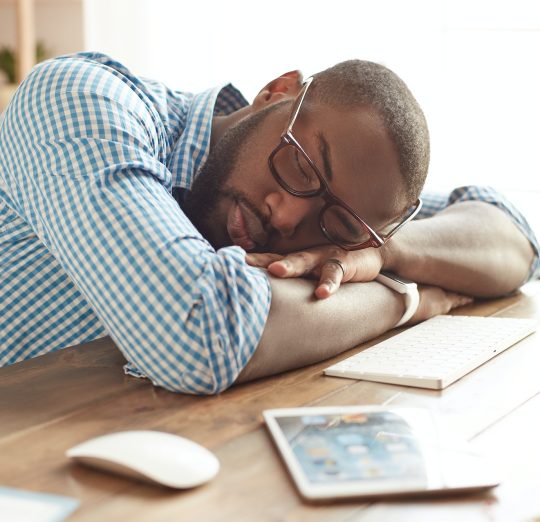 Taking a break. Tired afro american man in glasses sleeping at his working place at home. Afro